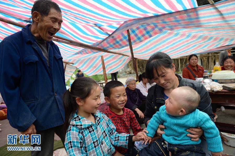 　4月21日，太平镇春光村溪口上组，张大爷（左）在逗不到8个月大的孙子。目前，“4·20”地震芦山县太平镇仍然余震不断。但在灾区的乡村，在临时扎起的帐篷里，随时可见孩子们天真的笑脸。突如其来的灾难给他们的家园留下了印记，但没能阻挡笑容在他们脸上绽放。有孩子，有笑容，就有希望。 新华社记者 李桥桥摄