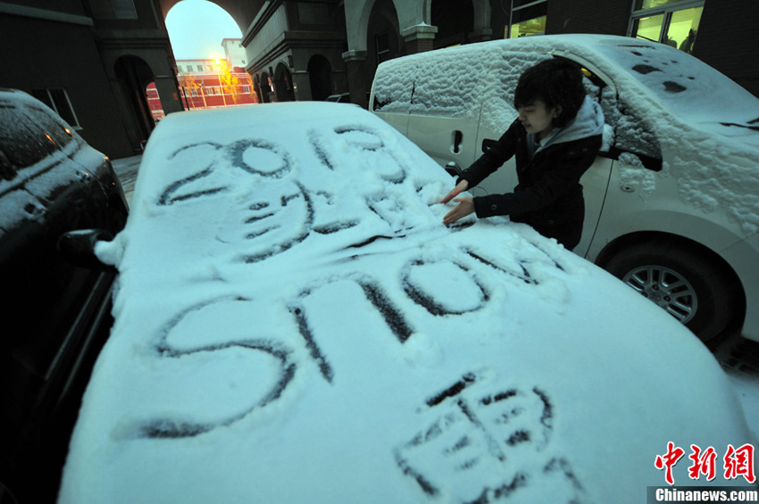 11月18日，行人在车辆的积雪上涂鸦。当日，沈阳迎来今年立冬后首场较强降雪。降雪从当日早间开始，直至下午5时仍在持续，风力较大，气温偏低，辽宁省内多条高速公路封闭。中新社发 于海洋 摄
