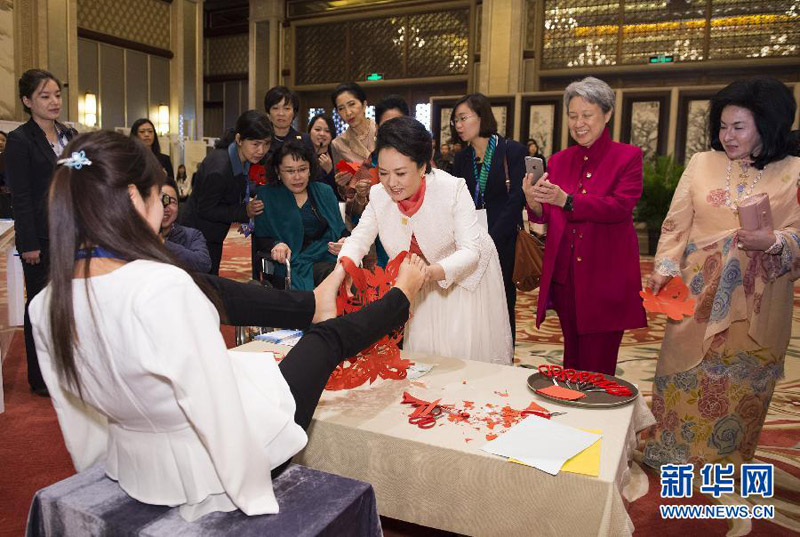 11月10日，国家主席习近平夫人彭丽媛同参加2014年亚太经合组织领导人非正式会议的部分经济体领导人夫人出席由中国残疾人联合会主办的“促进残疾人共享经济社会发展成果”主题系列活动。这是彭丽媛接过失去双臂的女青年夏红用双脚剪出的剪纸作品“和平鸽与爱心”。 新华社记者黄敬文摄