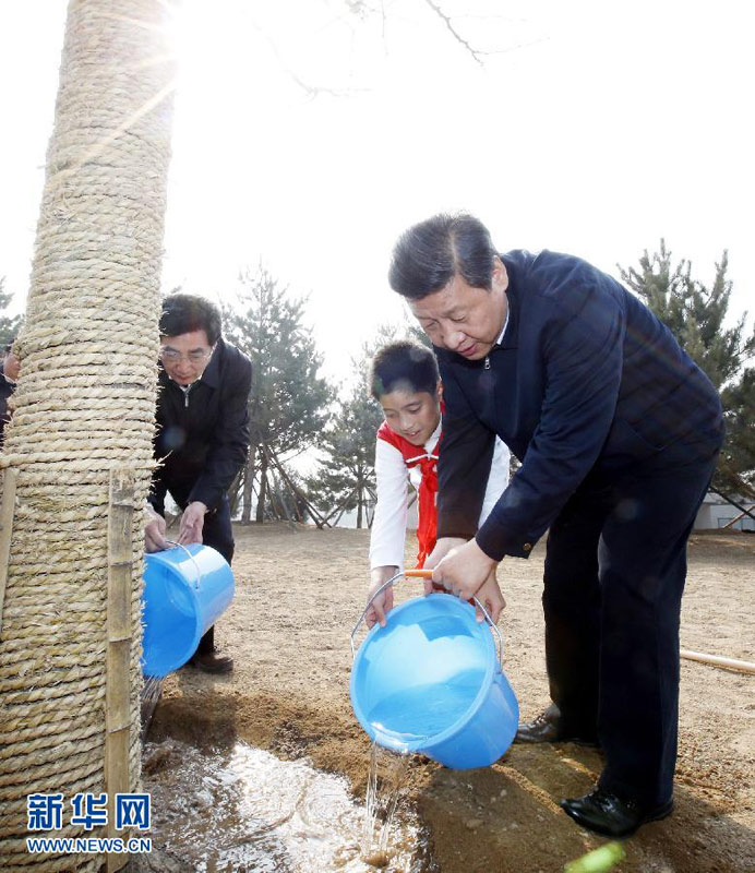 2013年4月2日，党和国家领导人来到北京市丰台区永定河畔参加首都义务植树活动。这是习近平同少先队员一起给刚栽下的银杏树浇水。新华社记者 鞠鹏 摄